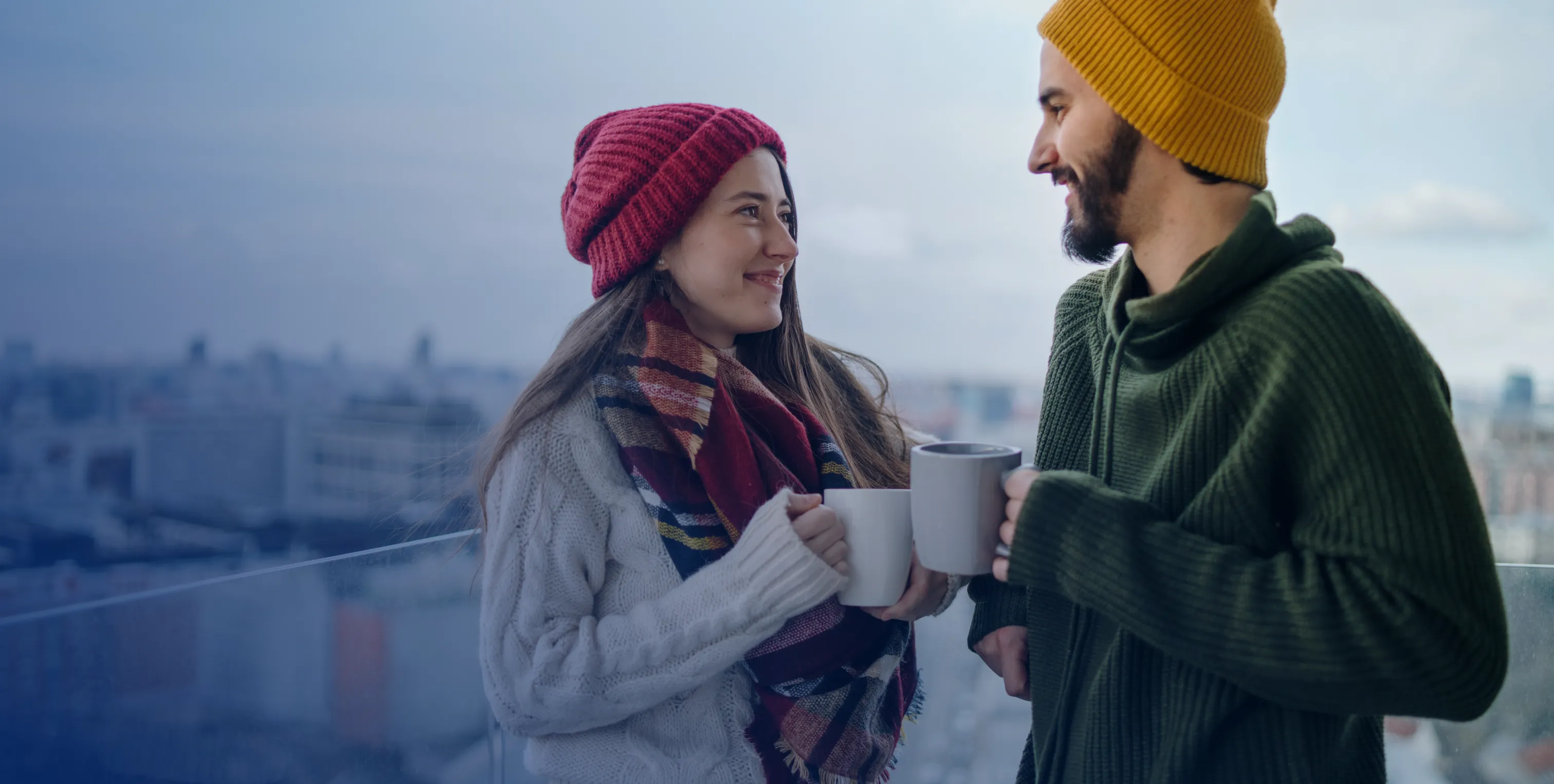 Two people drinking coffee out in the cold wearing wool sweaters.