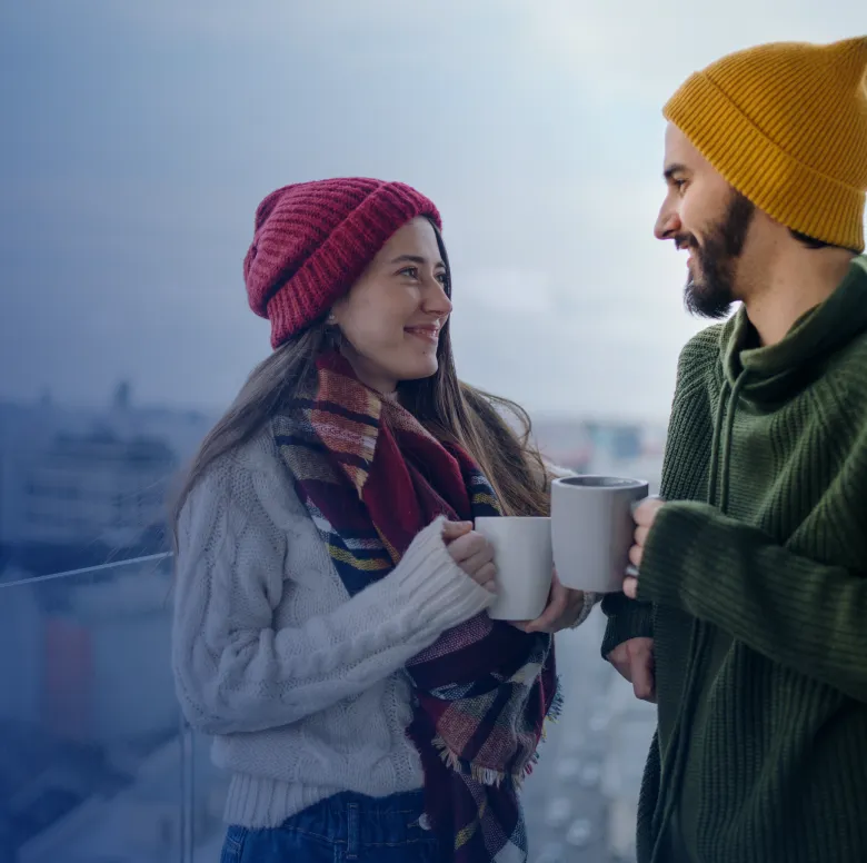 Two people drinking coffee out in the cold wearing wool sweaters.